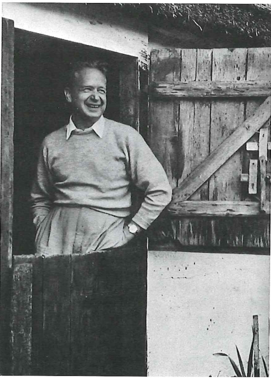 Dag Hammarskjöld standing, smiling, and looking out a barn door.